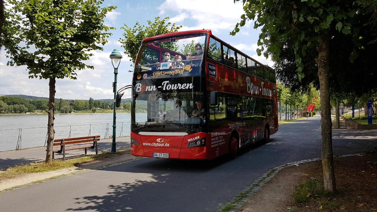 punane kahekordne buss sõidab mööda tänavat