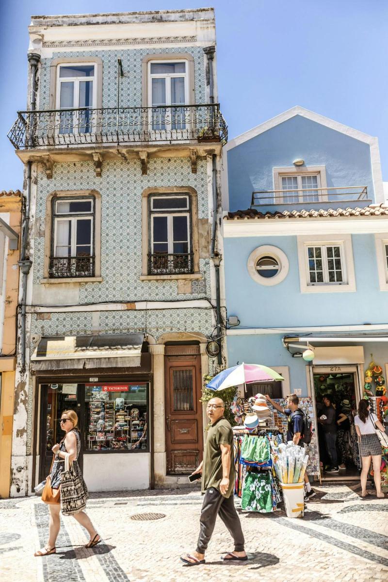 a man and woman walking down a street in front of buildings