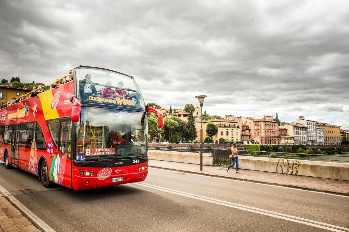 červený dvoupatrový autobus jedoucí po ulici