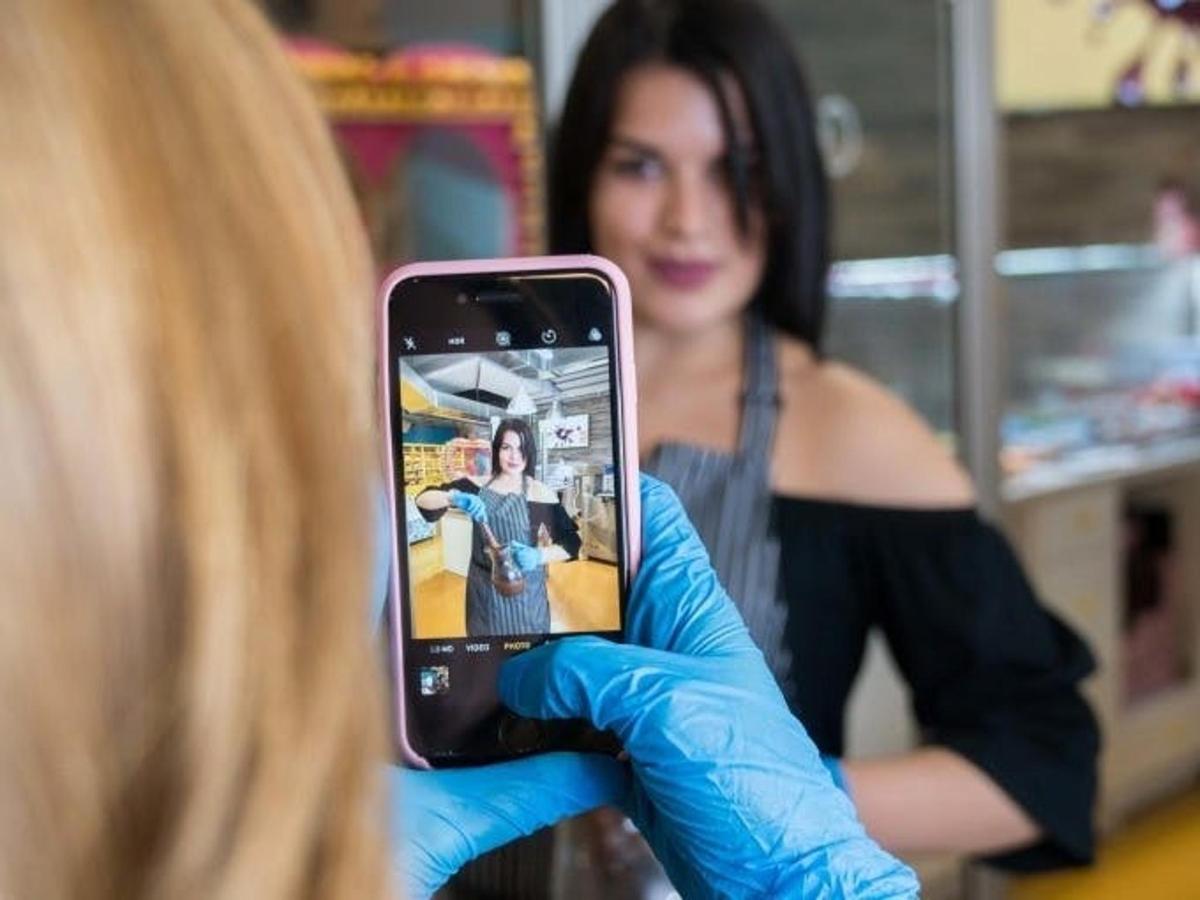 Una mujer con guantes azules sosteniendo un teléfono celular