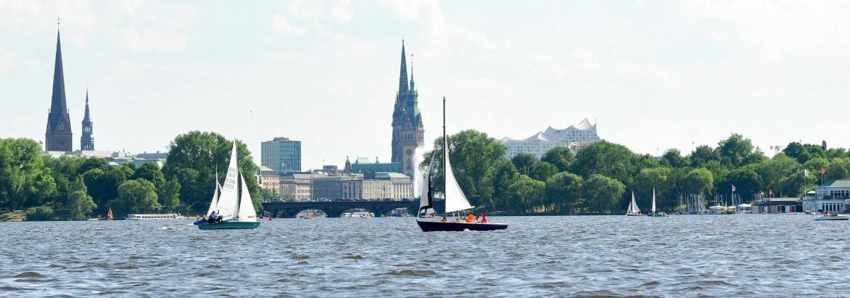 tiga perahu di air dengan kota di latar belakang