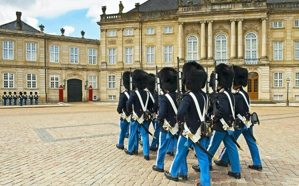 skupina lidí v uniformách stojící před budovou
