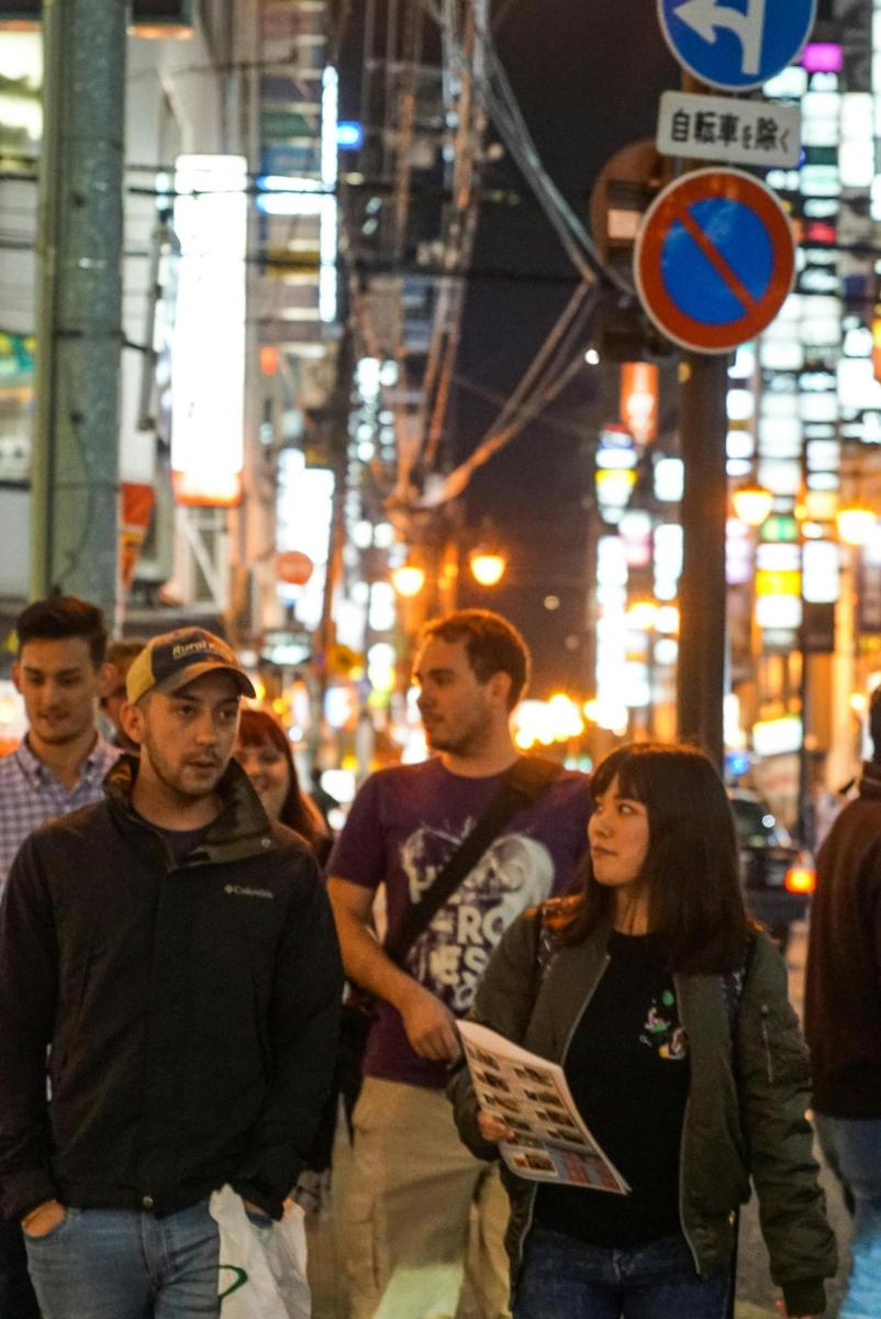 a group of people walking down a city street at night
