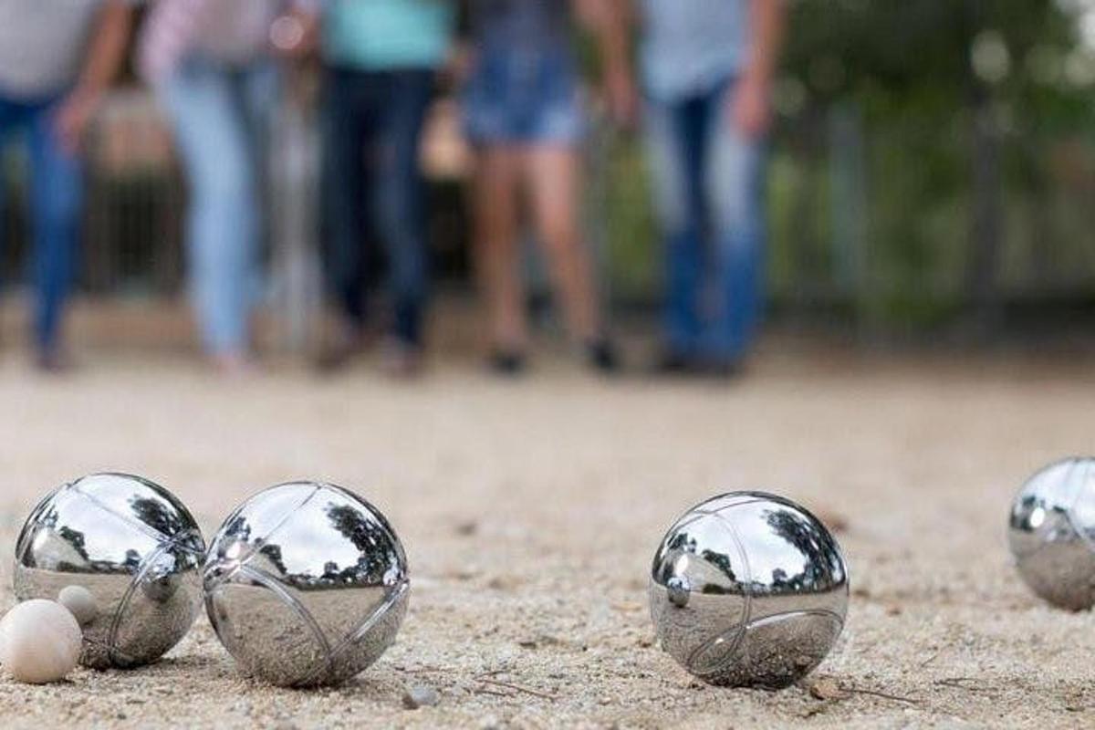 empat bola logam di atas tanah dengan orang di latar belakang