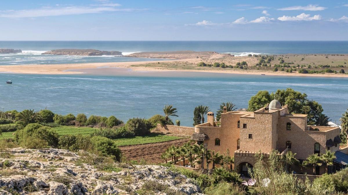 an old house on a hill next to the ocean