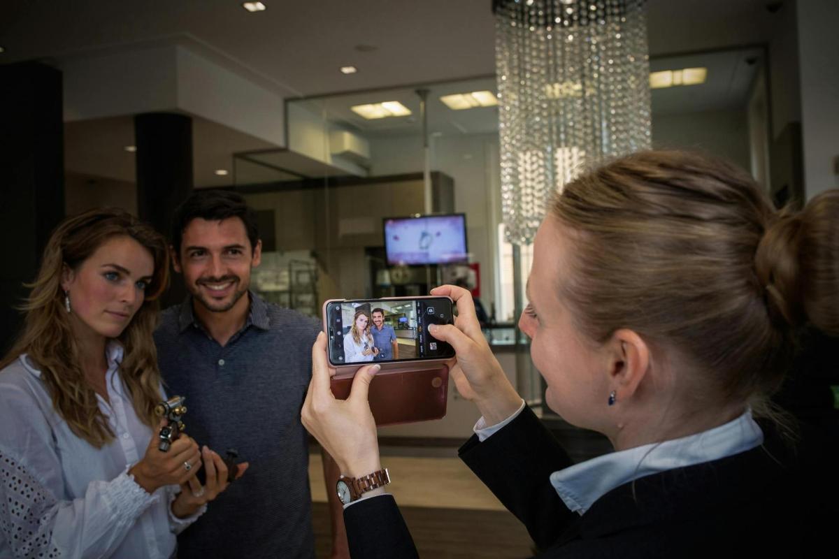 ženska, ki fotografira dve osebi z mobilnim telefonom