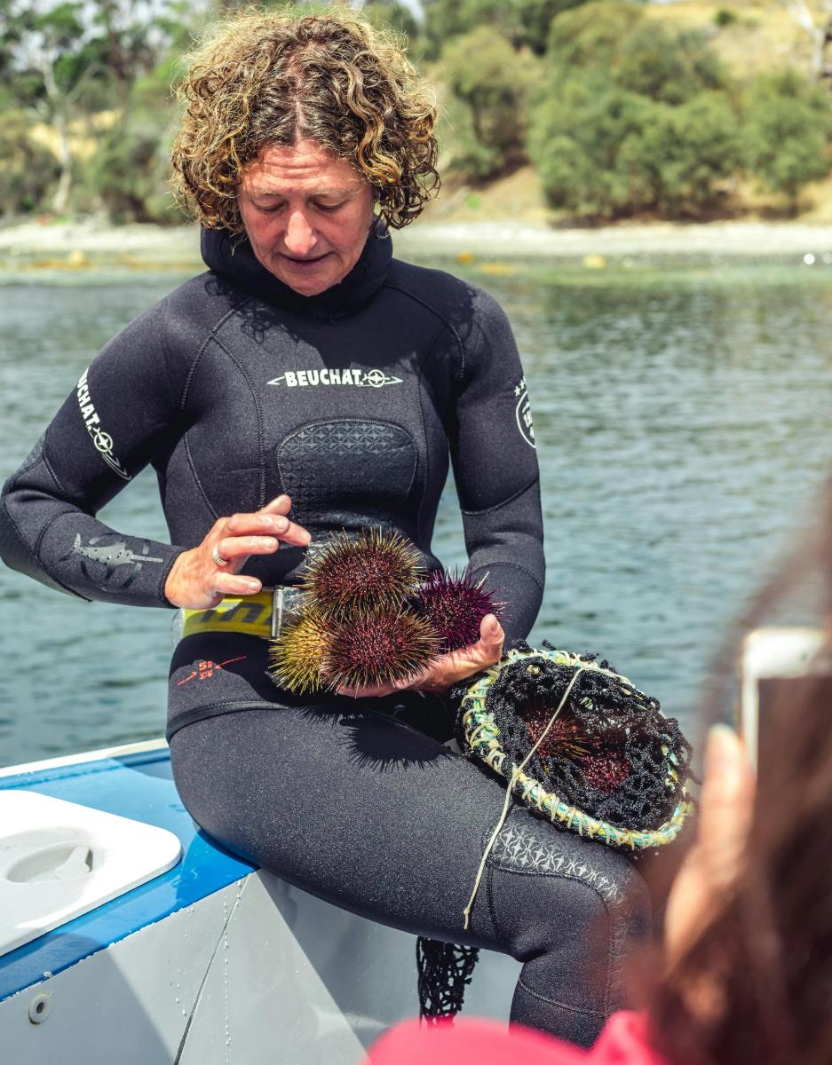 una donna in muta su una barca che tiene in mano un pesce
