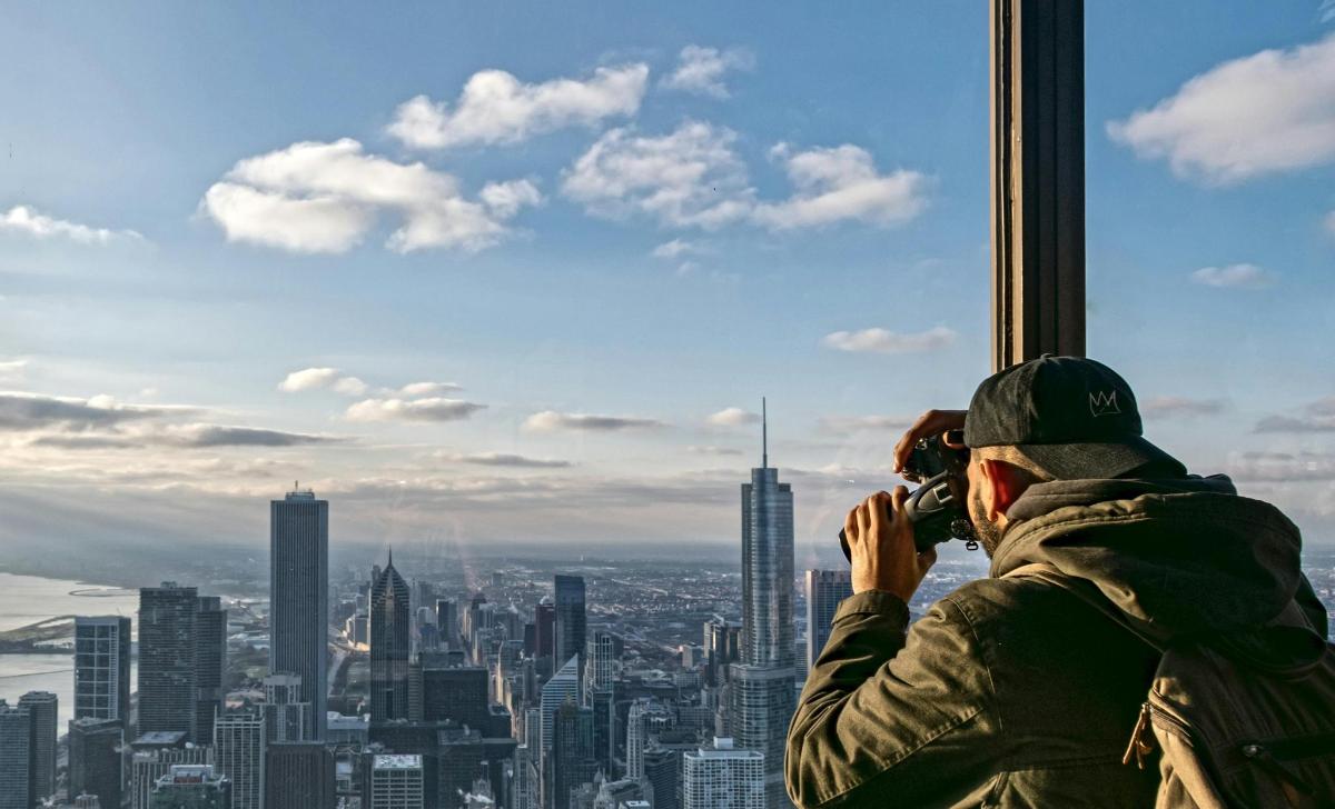 a man taking a picture of a city from a tower