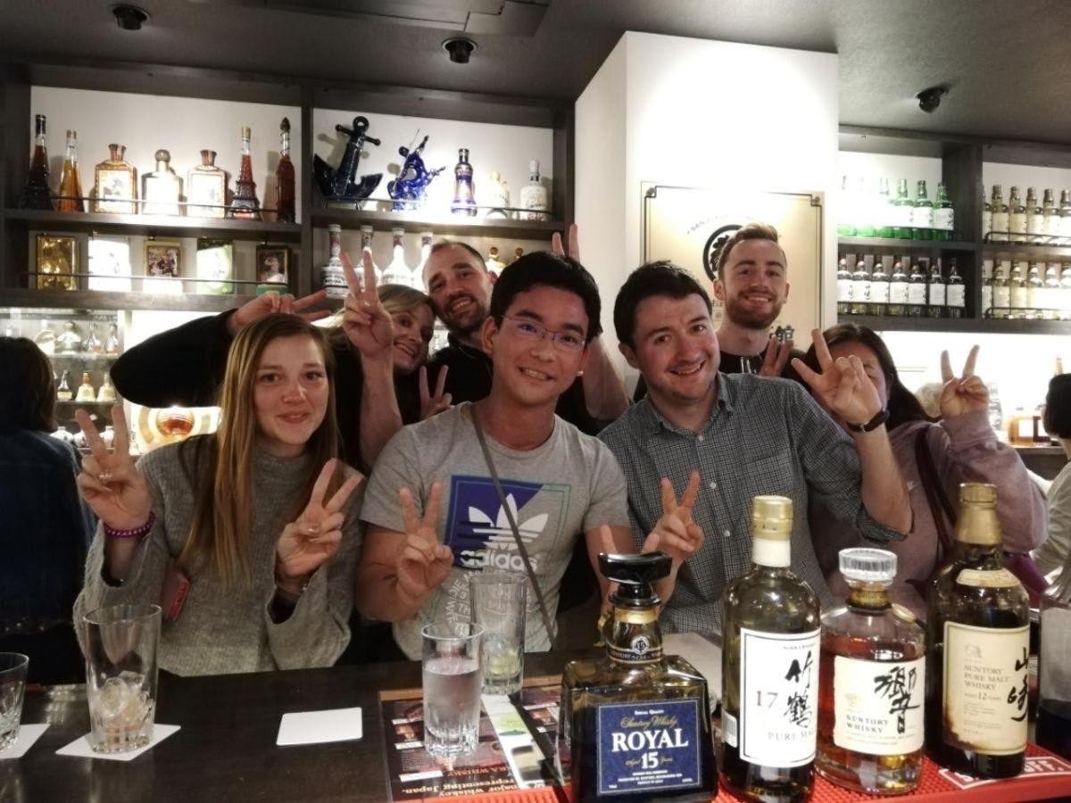 skupina lidí stojící za barem se zdviženýma rukama