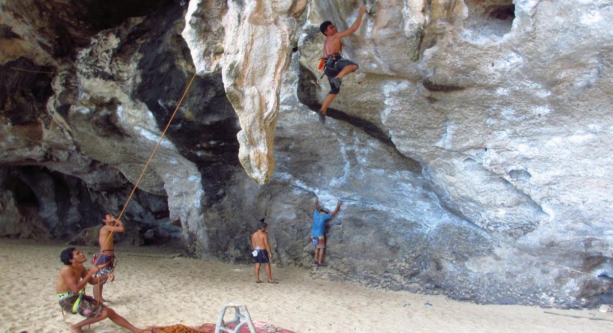 a group of men are climbing a rock wall