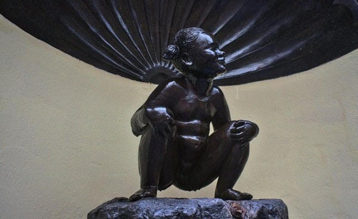 en bronsestatue av en mann som sitter på en stein