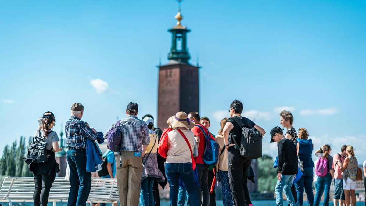 en gruppe mennesker stående foran et klokketårn