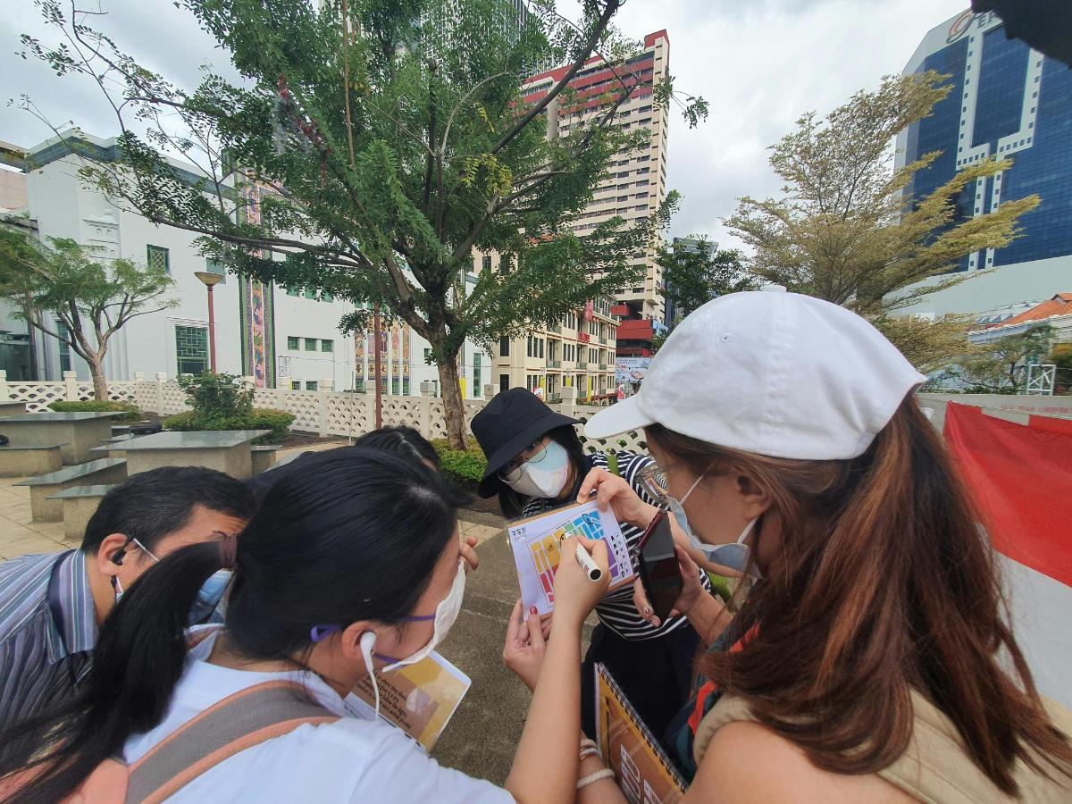 a group of people standing around looking at a book