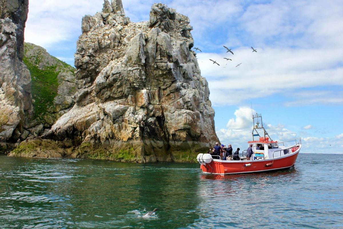 a boat in the water next to a rock formation