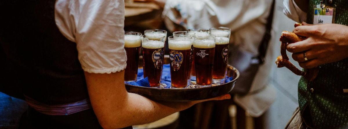 osoba držící podnos se sklenicemi piva