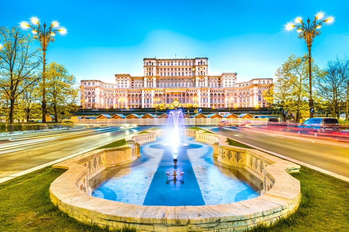 a large building with a fountain in front of a street