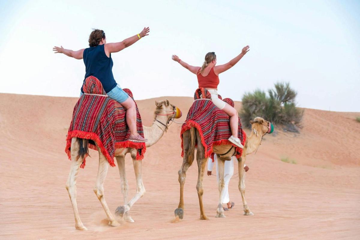 two women riding on camels in the desert