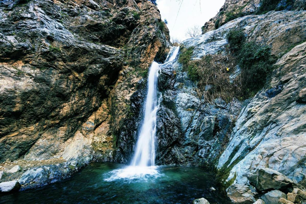 una cascata sul fianco di una montagna rocciosa