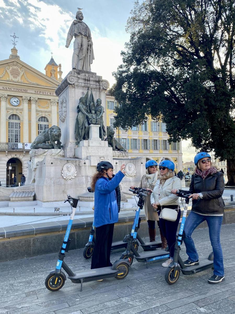 um grupo de pessoas com scooters em frente a uma estátua