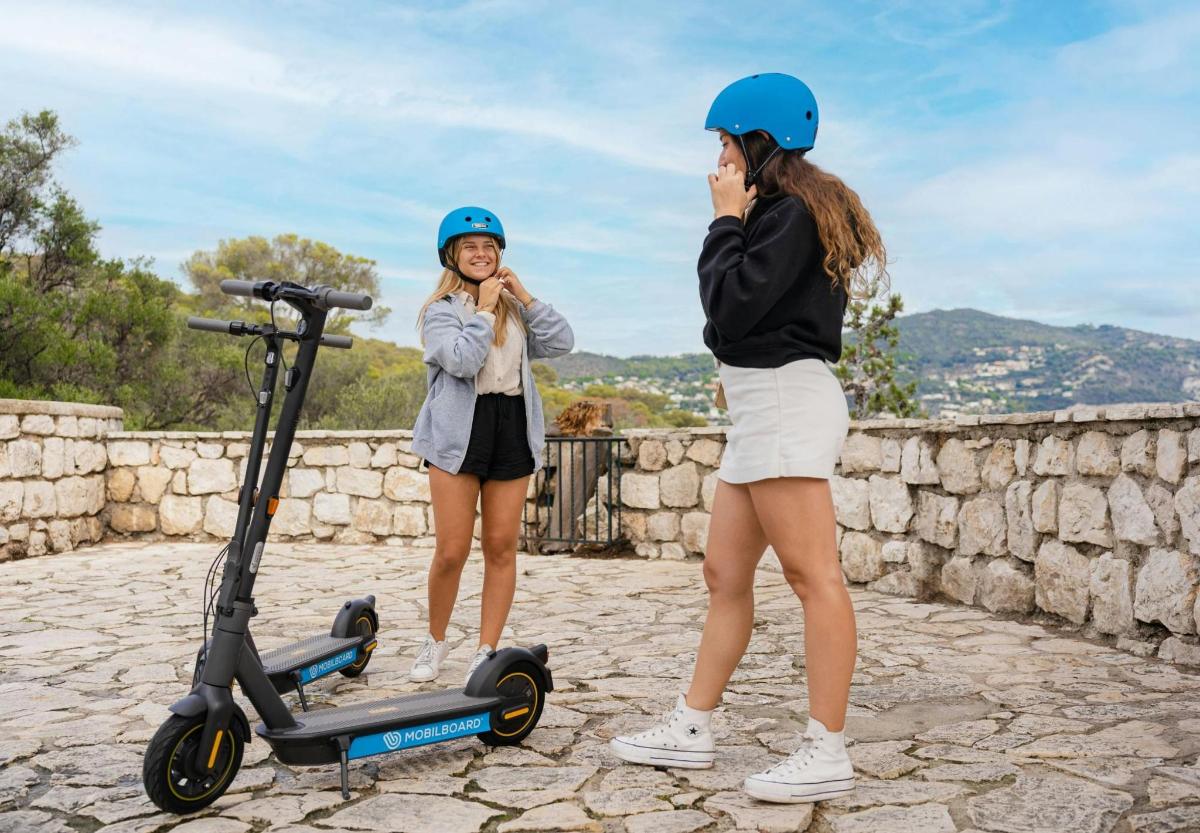 moteris, kalbanti mobiliuoju telefonu šalia motorolerio