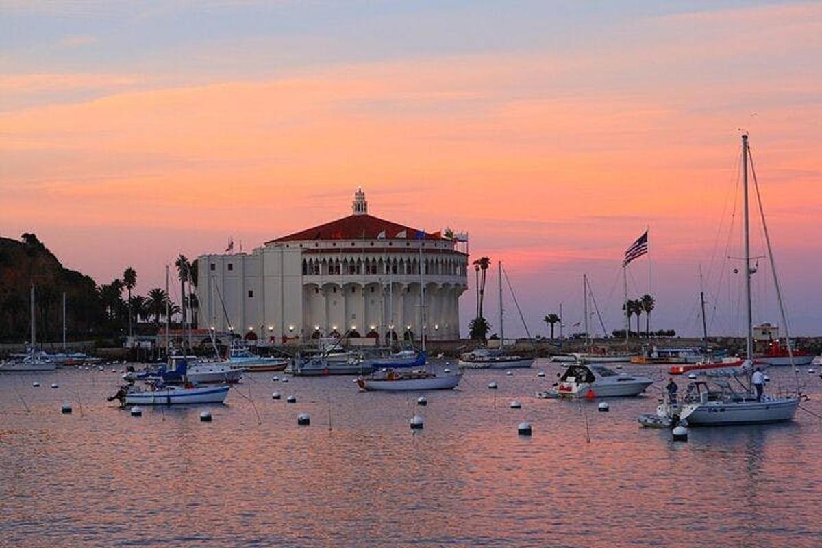 Un gran edificio con barcos en el agua al atardecer.