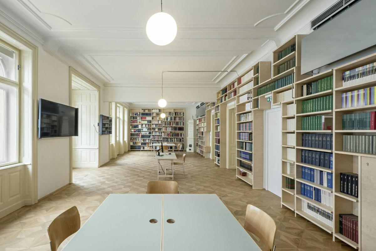 uma biblioteca com uma mesa branca, cadeiras e estantes