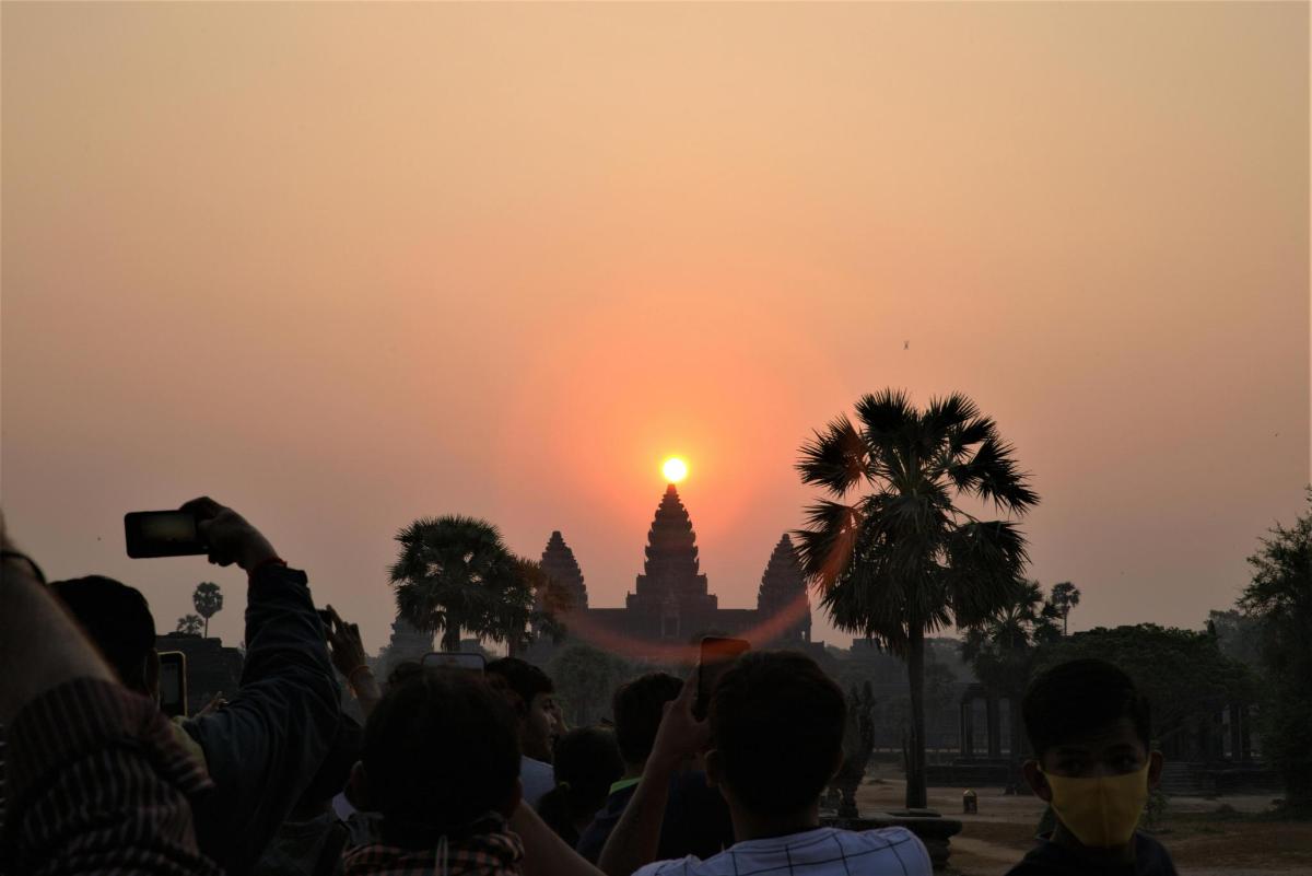 una multitud de gent fent fotos de la posta de sol