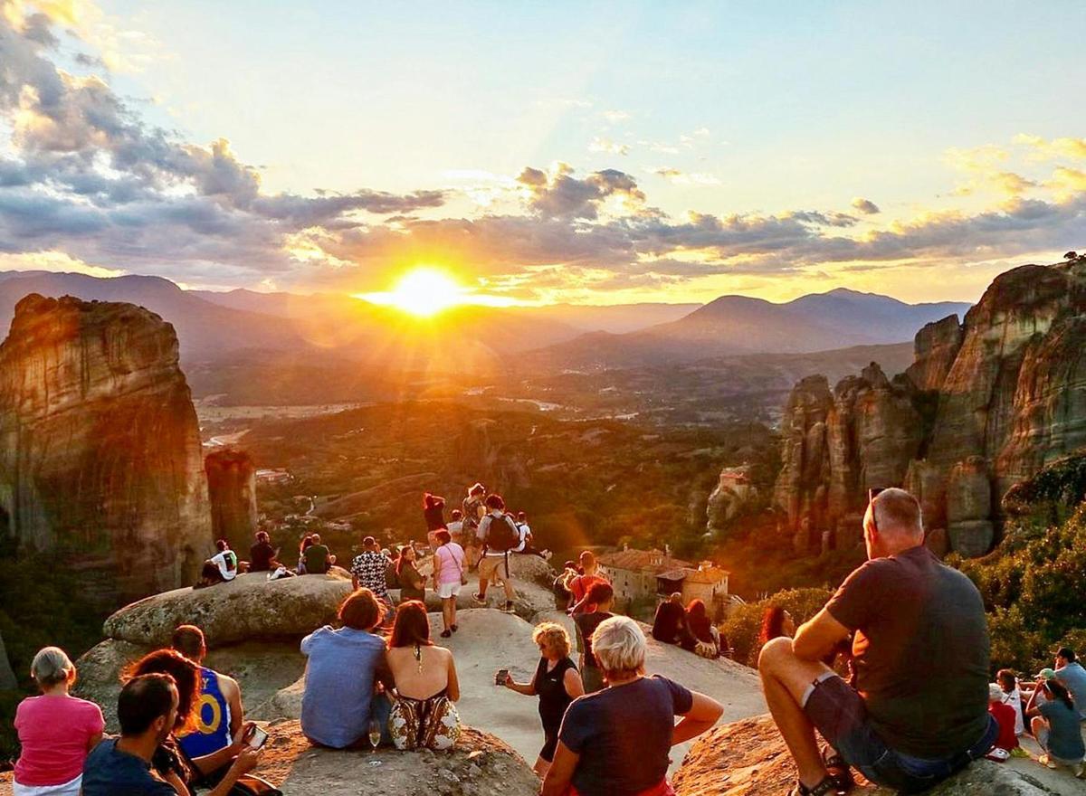 a group of people sitting on top of a mountain watching the sunset