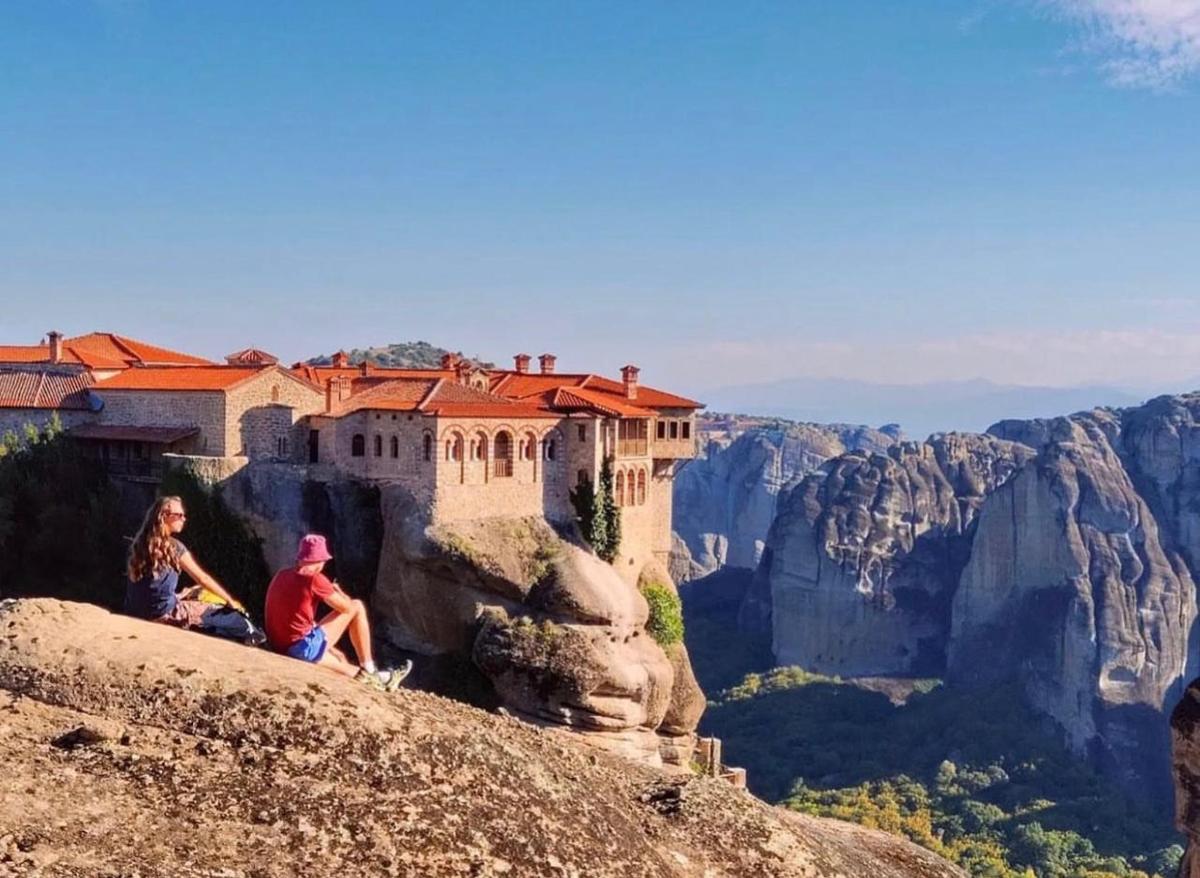 two people sitting on the edge of a mountain with a castle