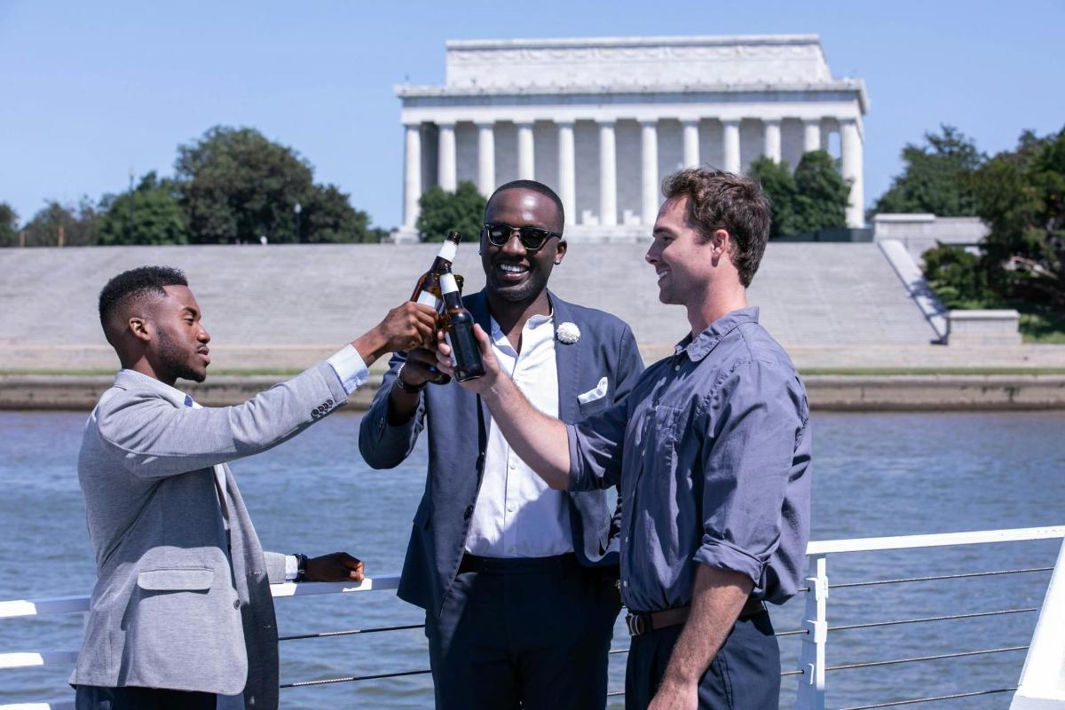 un uomo che scatta una foto a due uomini davanti al monumento a Washington