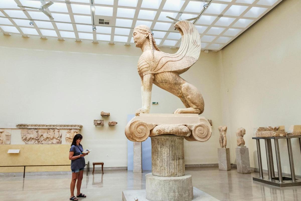 una donna in piedi davanti a una statua in un museo
