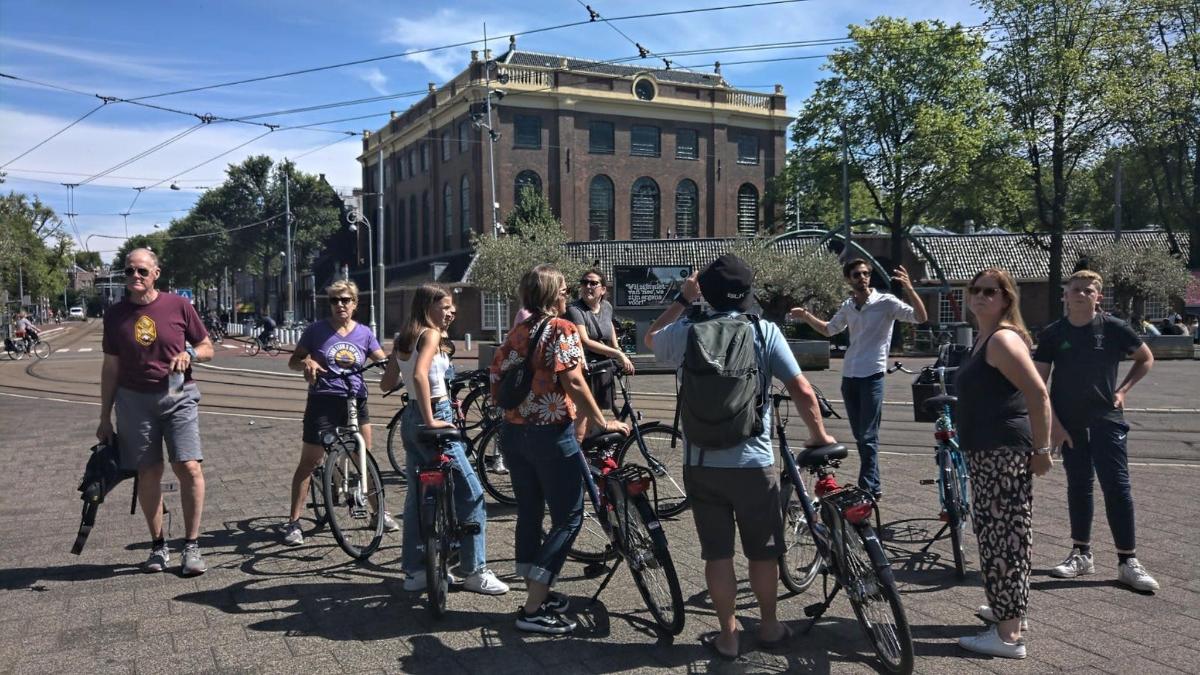 Un grupo de personas paradas en la calle con bicicletas.