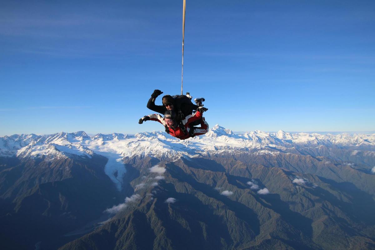 una persona colgando de una cuerda en la cima de una montaña