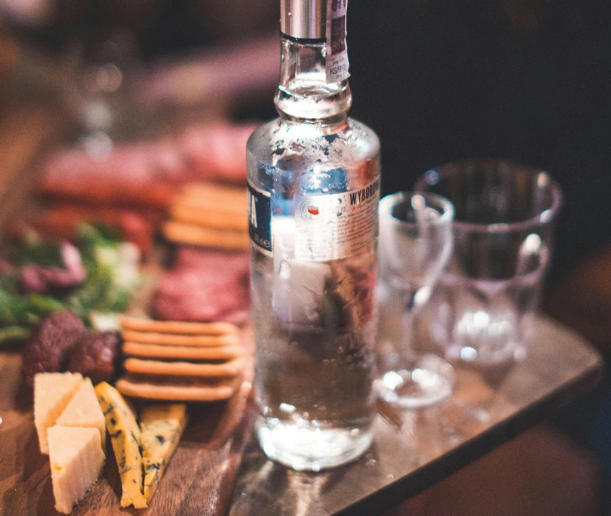 a bottle of water sitting on a table with cheese and crackers