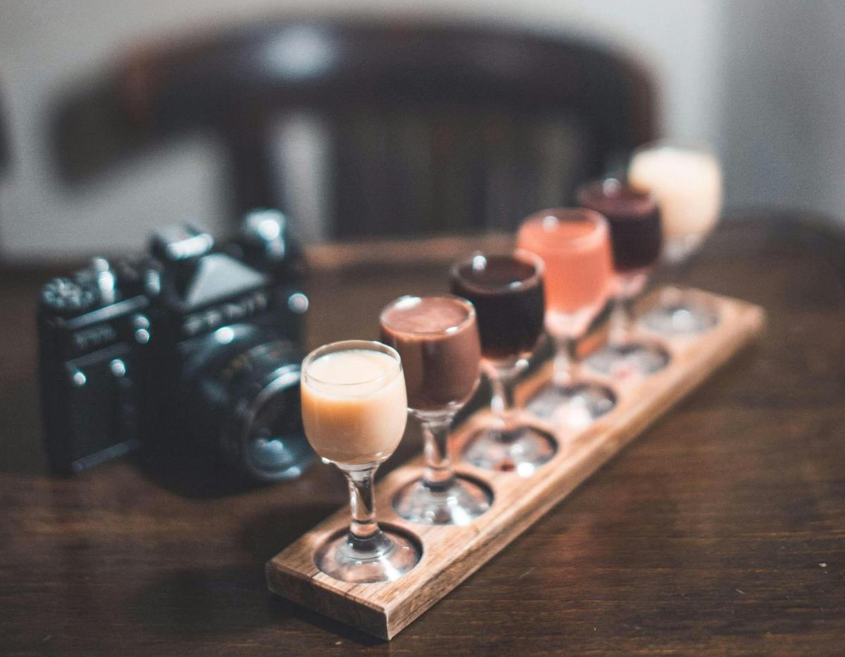 a row of wine glasses on a wooden table with a camera