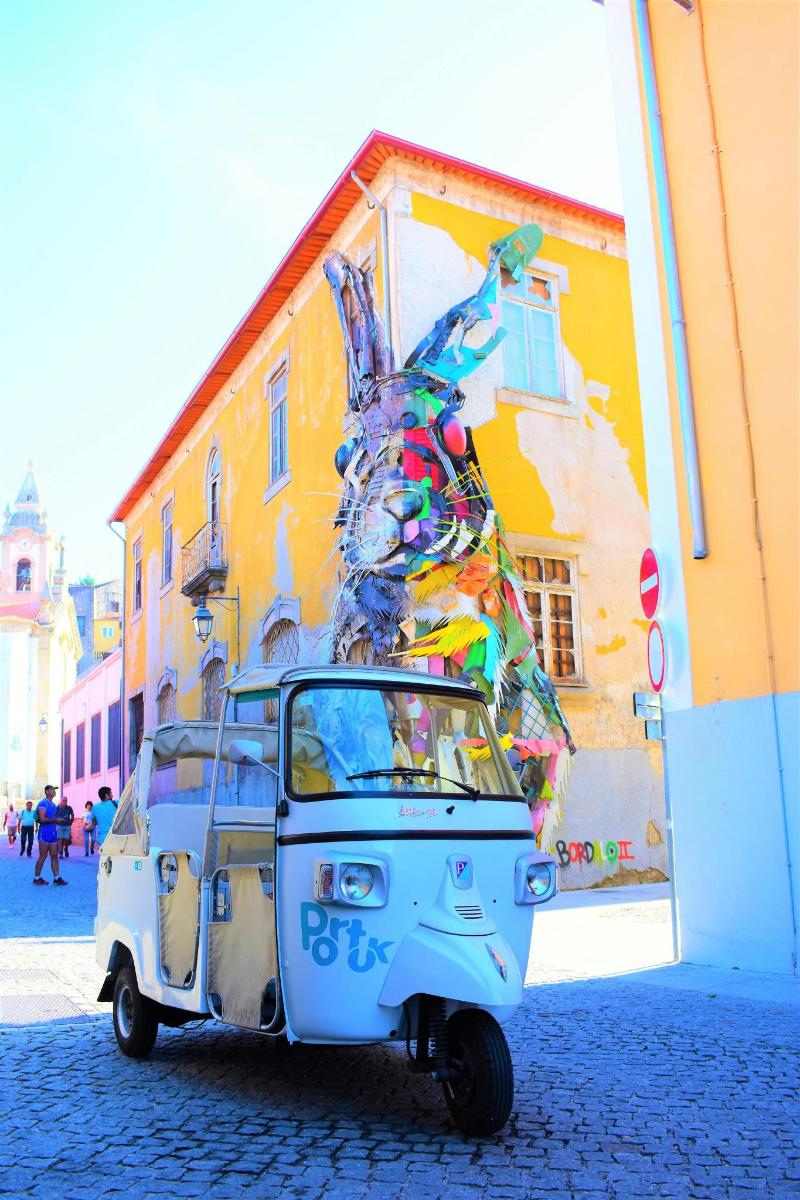 una piccola auto parcheggiata davanti a un murale