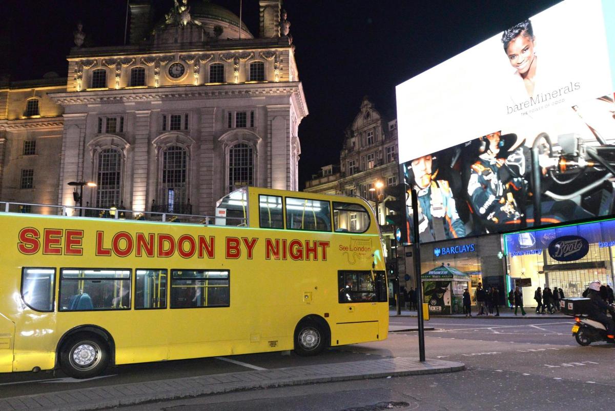 a yellow double decker bus on a city street at night