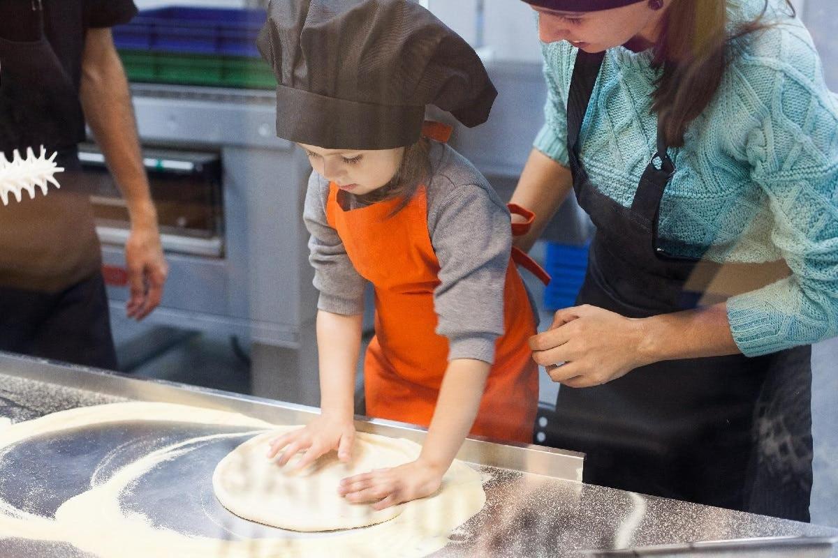 a woman and a child making a dough in a kitchen