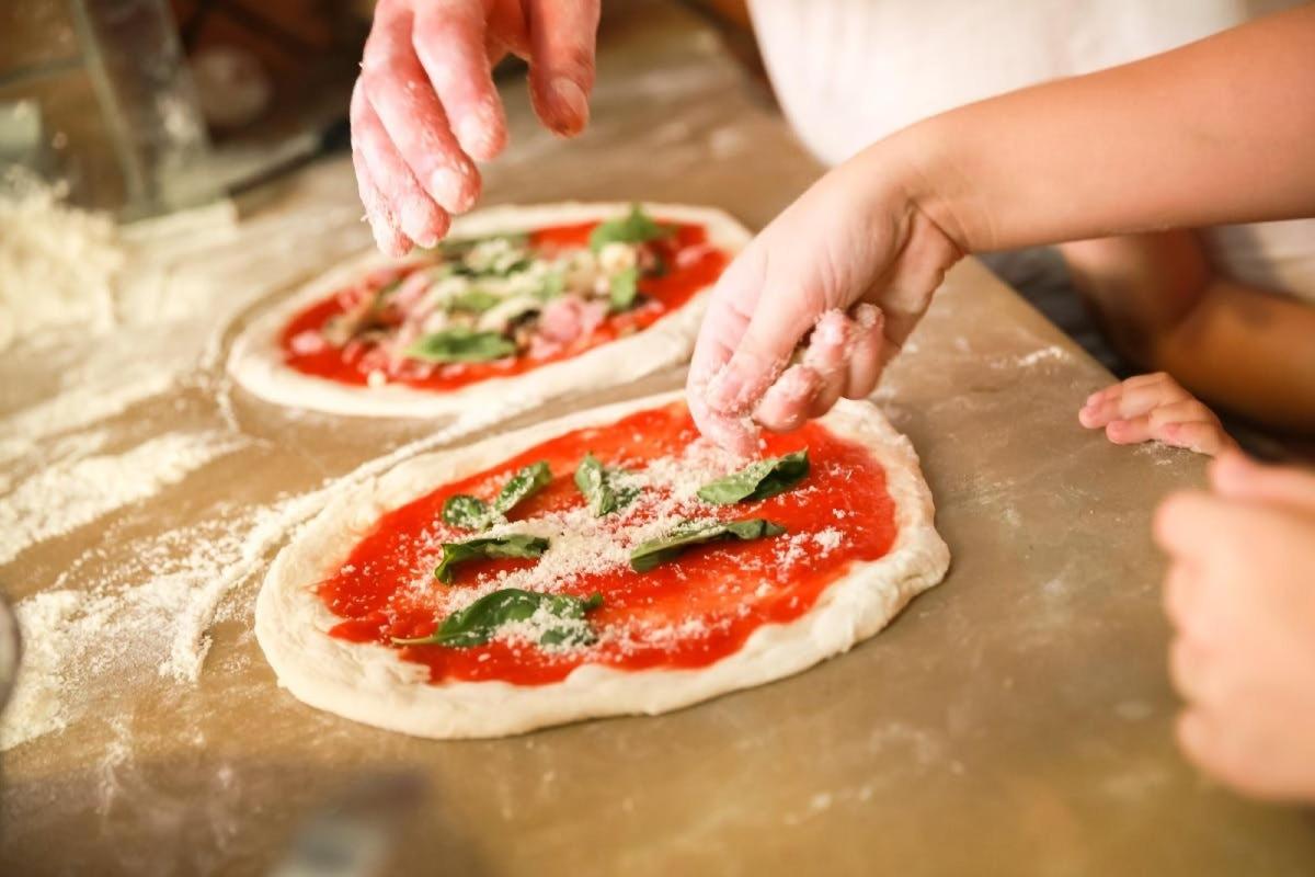 a person making two pizzas on a counter