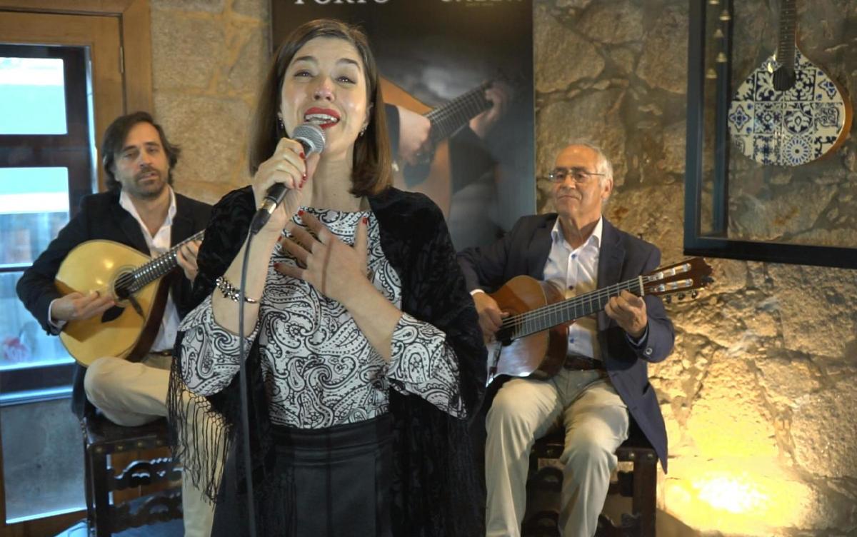 žena spievajúca do mikrofónu s dvoma mužmi hrajúcimi na gitarách