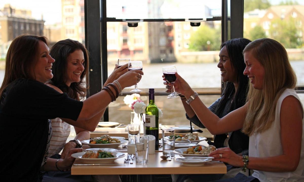 a group of women sitting around a table drinking wine
