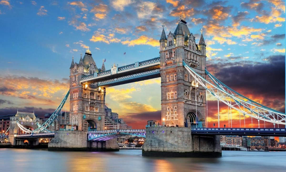 a suspension bridge over the water with a sunset