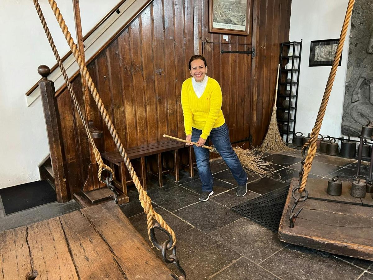 un uomo con un maglione giallo in piedi in una stanza con delle corde