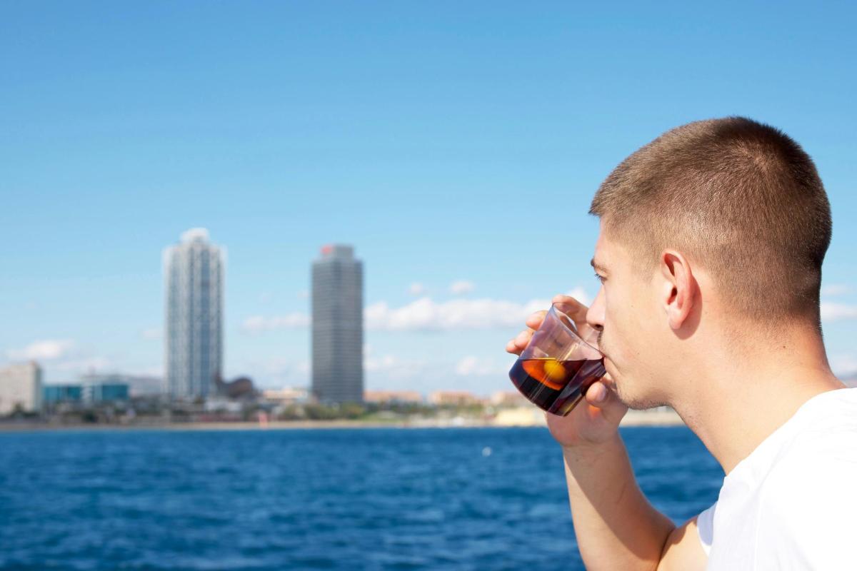 um homem bebendo uma taça de vinho perto da água