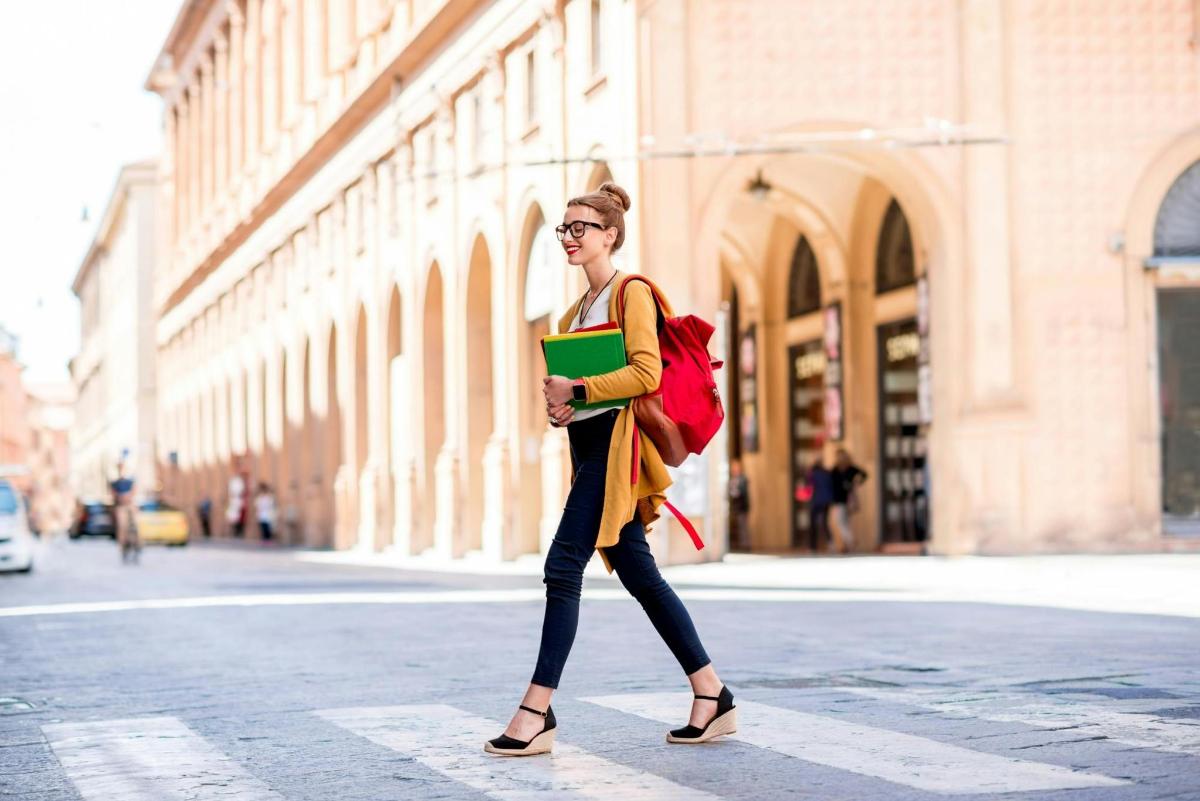 una dona caminant pel carrer amb un llibre