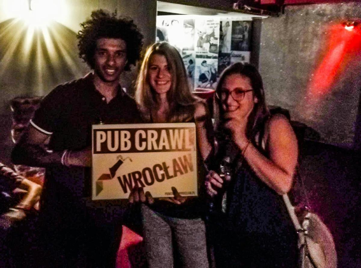un grup de trei persoane care țin un semn de deviere a vizitei la pub-uri