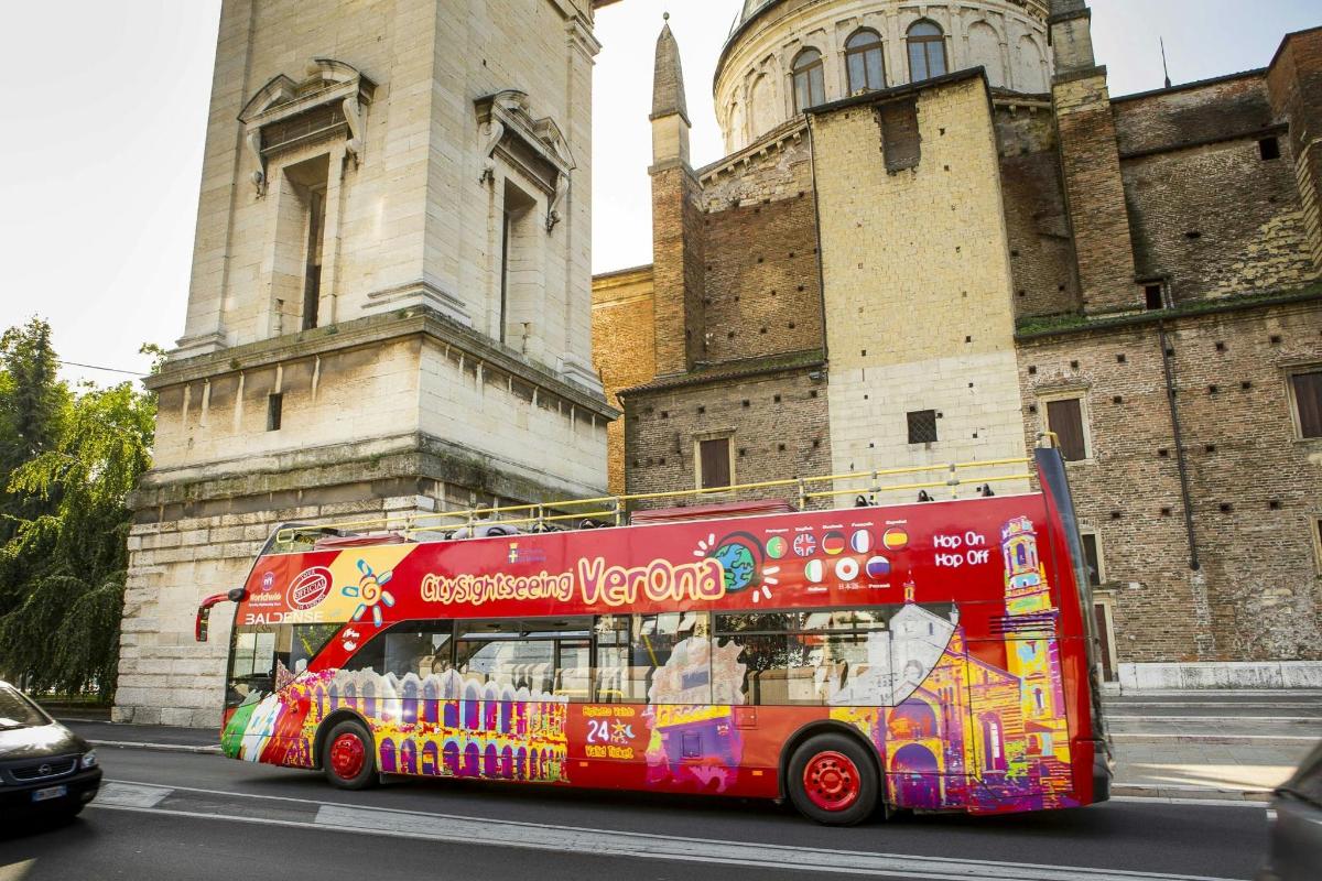 rdeč dvonadstropni avtobus, ki se pelje mimo stavbe