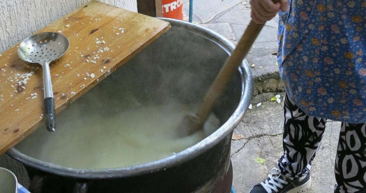 člověk míchá hrnec dřevěnou lžící