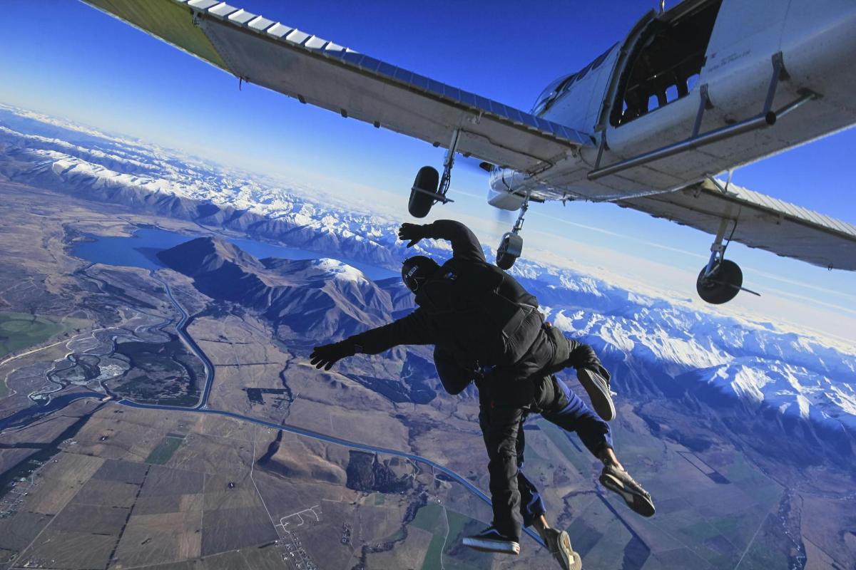 a man is hanging from the wing of an airplane