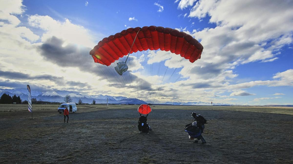 a group of people flying a large red parachute